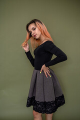 Lovely cute young woman in elegant  black dress isolated on dark green background