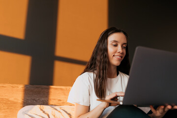 Close up portrait of brunette woman is typing on laptop. Freelancer working from home.Beauty in white shirt spends time doing useful activities. Education concept.