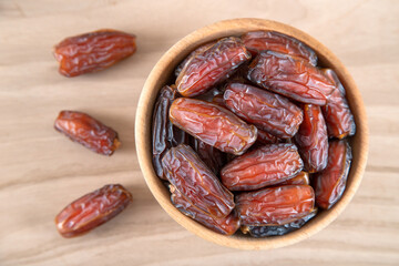 Date fruit in bowl on wooden background, top view