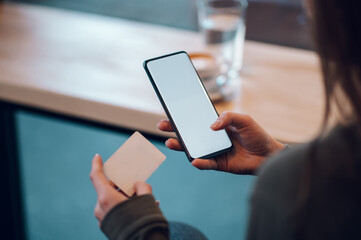 Close up of a woman hands using smartphone and a credit card