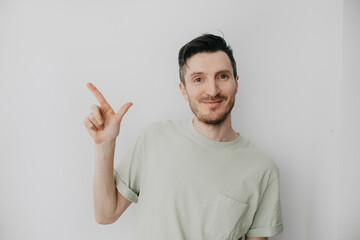 Fototapeta premium Handsome young man over grey wall with happy face pointing his finger
