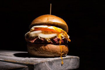 Home made tasty burger on wooden table and black background