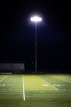 Stadium lights on a poll next to American football high school field with artificial grass surface