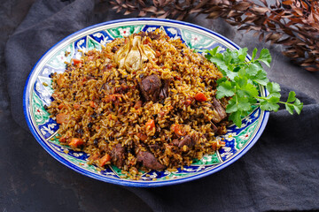 Traditional Uzbek fergana plov with devsira rice and lamb meat served as close-up on a handmade painted lagan platter