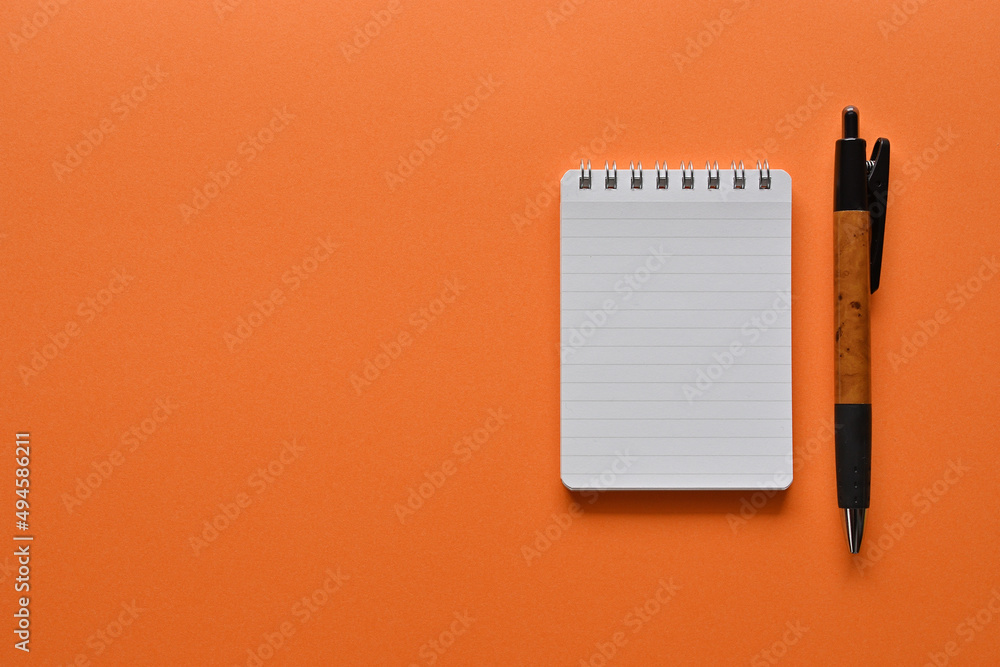 Aufkleber a notebook and pen in a simple composition on orange background. copy space available.