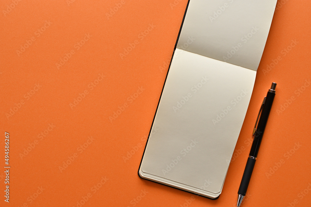 Aufkleber a notebook and pen in a simple composition on orange background. copy space available.