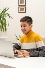 Shot of young boy using a laptop  for playing games in the room.