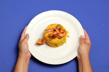Paella rice is a traditional cuisine recipe from the city of Valencia Spain prepared with saffron, seafood, shrimp, vegetables served on a white plate
