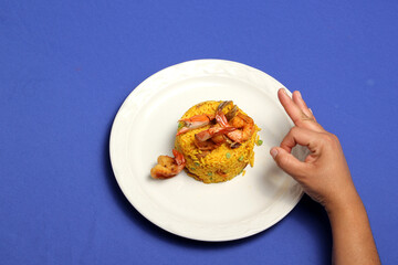 Paella rice is a traditional cuisine recipe from the city of Valencia Spain prepared with saffron, seafood, shrimp, vegetables served on a white plate
