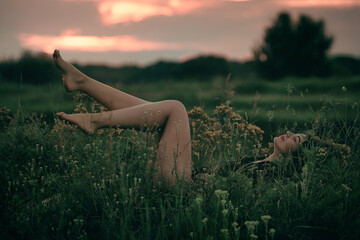 Beautiful girl in a bodysuit lies in the grass