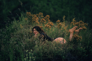 Beautiful girl in a bodysuit lies in the grass