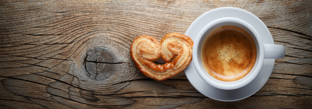 Espresso cup and puff pastry fan on wooden background, top view, space for text, flat lay.