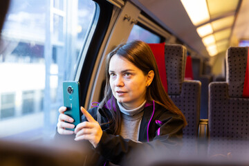 European woman taking pictures with her smartphone during train ride.