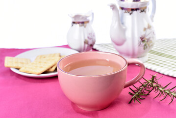 pink cup with lemon balm green tea, crackers old porcelain teapot in the background