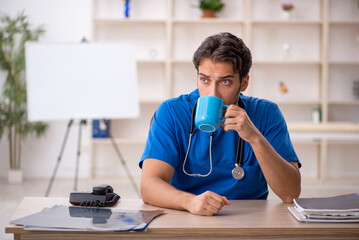 Young male doctor drinking coffee during break