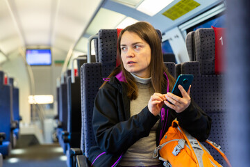 Caucasian woman using her smartphone while traveling by train.