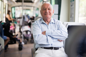 Elderly Caucasian man sitting in tram and looking in camera. - obrazy, fototapety, plakaty