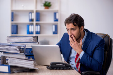 Young male employee and too much work in the office