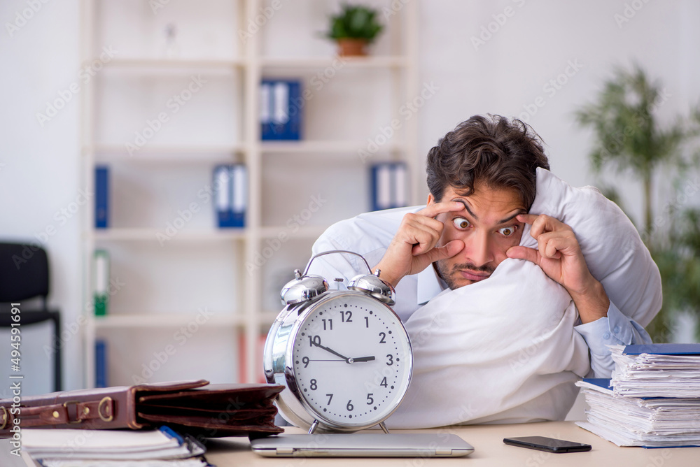 Wall mural young male employee in oversleeping concept