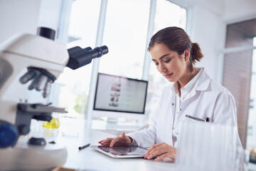 I must always keep track of all the work. Shot of a focused young female scientist working on a...