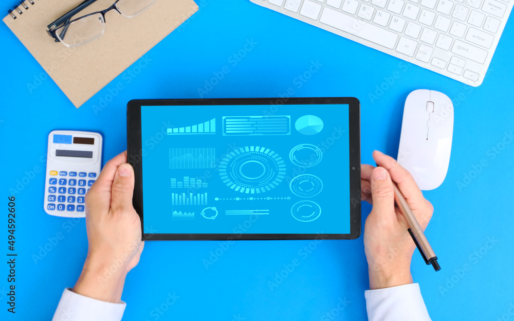 Poster top view hand working a tablet with growing virtual hologram of statistics, graph and chart.chart gr