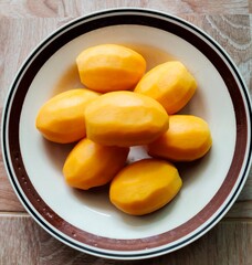Sweet marian plum peeled in plate on wooden background