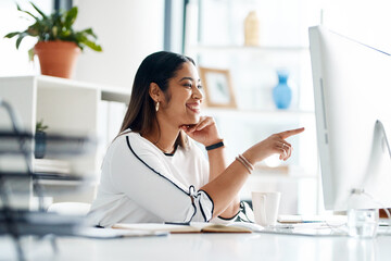 Looks like she found something useful. Shot of a young businesswoman working on a computer in an office.