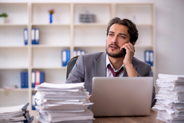 Obraz premium Young male employee and too much work in the office