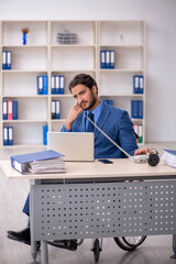 Young male employee in wheel-chair sitting in the office