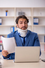 Fototapeta na wymiar Young male employee after accident sitting at workplace