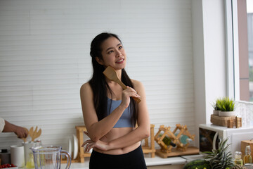 young Asian woman cooking vegetable healthy food and eating or drinking in home kitchen