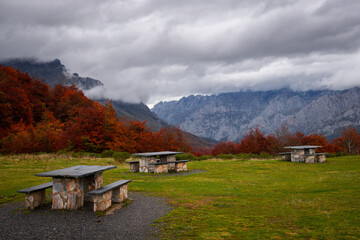 Puerto de Panderrueda viewpoint with picnic tables on a colorful autumn mountain range landscape on a cloudy day, Spain