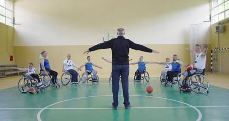 the selector of the basketball team with a disability stands in front of the players and shows them the stretching exercises before the start of training - Powered by Adobe