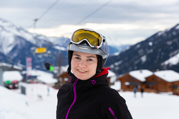 Fototapeta na wymiar Closeup portrait of positive woman in ski helmet and glasses enjoying vacation in alpin ski resort on sunny winter day. Active holidays concept