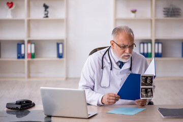 Old male doctor radiologist working in the clinic