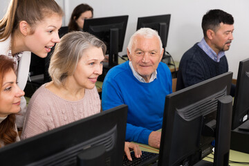 Fototapeta premium Young and mature coworkers working around computer monitor in office