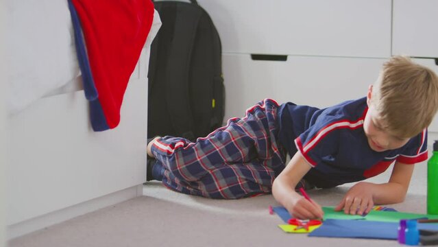 Boy wearing pyjamas in bedroom making card to celebrate birthday or mothers day - shot in slow motion