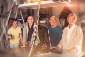 Group photo of grandparents and grandkids standing in escape room at table with computer on it.