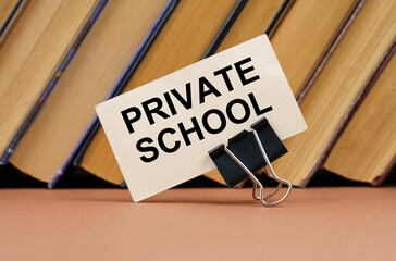 On the table against the background of books is a business card with the inscription - Private School