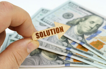 In the hands of a man is an arrow with the inscription - SOLUTION, in the background there are dollars.