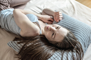 Young happy woman woke up in the morning and is lying in bed with enjoyment. Concept of healthy sleep, comfort and a pleasant start to a new day