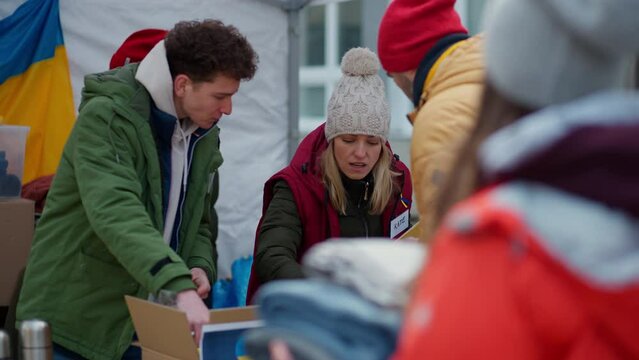 Volunteers distributing food and drink to refugees on the Ukrainian border, humanitarian aid concept.