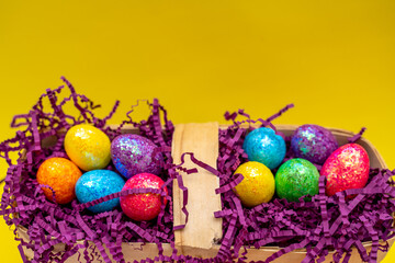 Easter composition from a basket and colored eggs prepared for the holiday on a yellow background