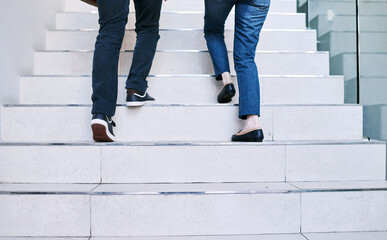 Reaching their goals together. Rearview shot of two unrecognisable businesspeople walking up a...