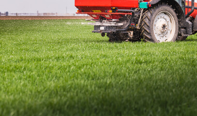 Tractor spreading artificial fertilizers in field