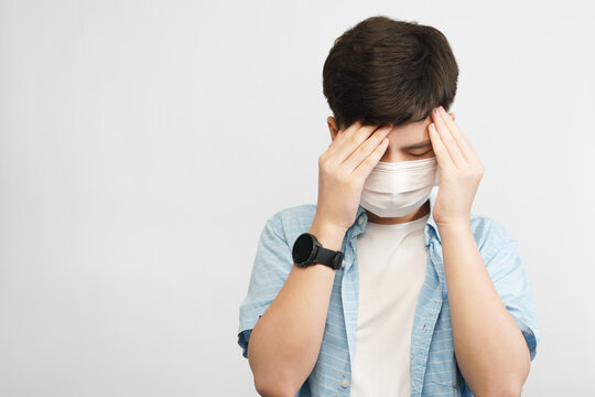 Teen Mental Health During COVID-19 Concept. Portrait Of An Asian Teenager Boy With Medical Face Mask, Face Down Hands Cover His Face. Stressful, Anxiety, Illness, Infected, Cyberbully, Pandemic.