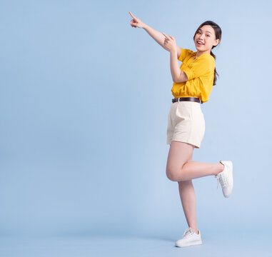 Full length image of young Asian woman posing on blue background