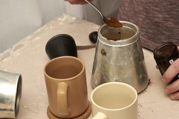 a person prepares coffee in a geyser, pours ground coffee into a geyser strainer
