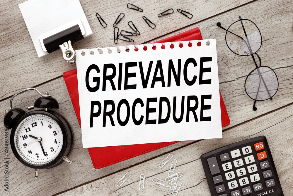 Poster grievance procedure text on a piece of paper with text on a red notepad
