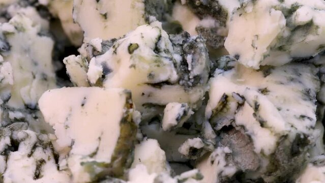 Macro shot of roquefort cheese chopped in small pieces. Rotating close up view in 4k.